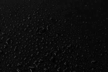 Water droplets on a dark surface create a pattern with reflections and shadows in a close-up view during a quiet moment