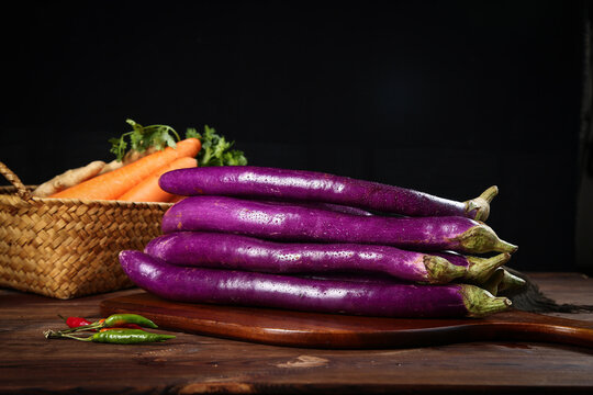 Fresh Purple Eggplants and Farm Produce on Rustic Farmhouse Table