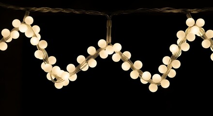 String lights forming a whisk shape against a dark background bulbs white