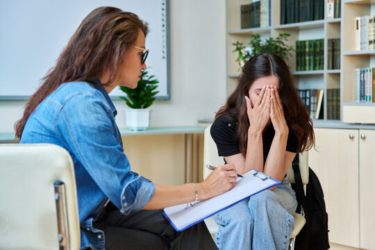 Sad teenage girl in mental therapy session, talking with school counsellor