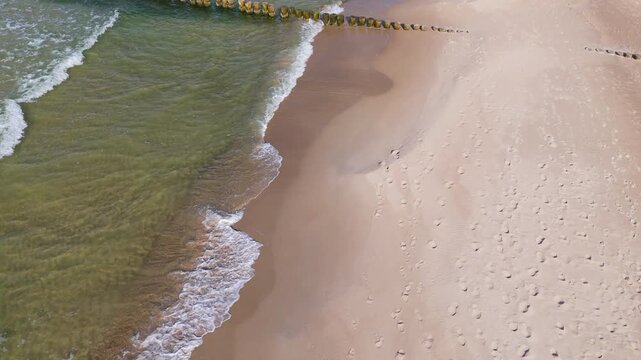 Coastline view that shows waves and sandy shore at midday