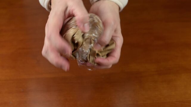 Hands crumpling a brown paper bag with sound
