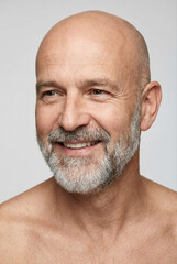 Obraz premium Close-up studio portrait of a smiling, bald, bearded adult man with a confident expression.