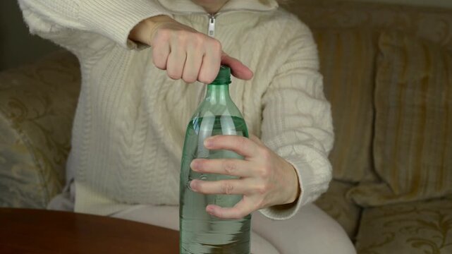Uncapping and opening plastic bottle of a hissing drink with the crisp twist-off of a plastic cap, followed by a sharp, gas release (hissing) and the lingering fizzing of bubbles with sound.