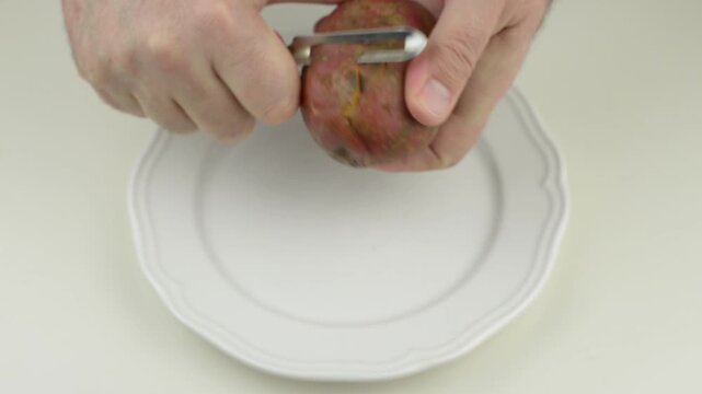 Peeling raw potato with a peeler with sound