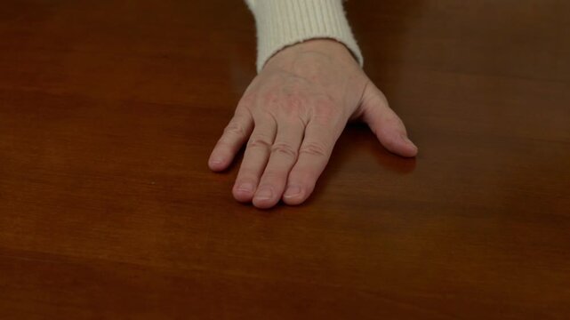 Hand rocking on a wooden table making a creaking sound. Close up of palm pressing wooden furniture producing a loud creak with sound