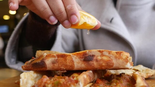 Hand Squeezing Fresh Lemon Juice Over Delicious Turkish Pide