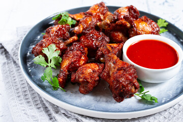 Fototapeta premium Crispy pieces of fried chicken, on a plate with sauce and herbs, in a modern kitchen environment, there are no people