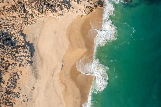 Aerial view of the beach with waves breaking on the shore in Baja California Sur, Mexico.