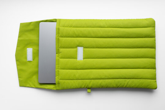 Green padded laptop sleeve with notebook isolated on white, flat lay.