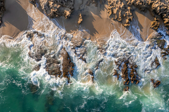 Aerial view of the beach with waves breaking on the shore in Baja California Sur, Mexico.