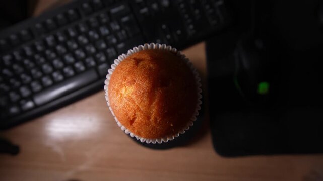 A close-up shot of a golden-brown muffin in a white paper wrapper, highlighting its perfectly domed top and slightly crisp texture. 