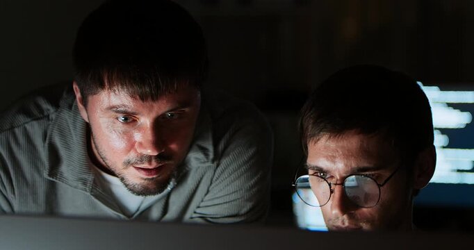 Two white Caucasian male software developers work late night on program coding, home office. People teamwork, computer engineering job, data scientist, cybersecurity, information technology. Close up