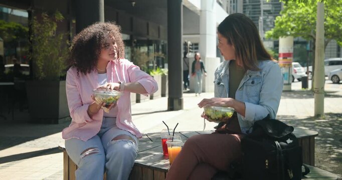 African American women friends on bench placing drinks, fumbling lids, opening bowls, eating lunch