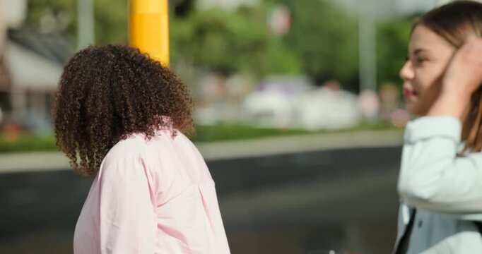 African American women pausing at yellow pole at curb scanning traffic checking watch then crossing