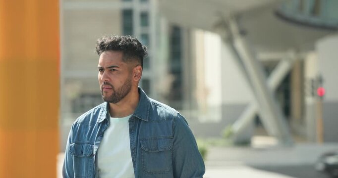 African American man walking from right scanning plaza by orange column, reacting, smiling in denim