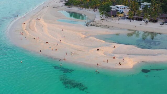 Drone view of crowded tropical beach with swimmers in shallow water