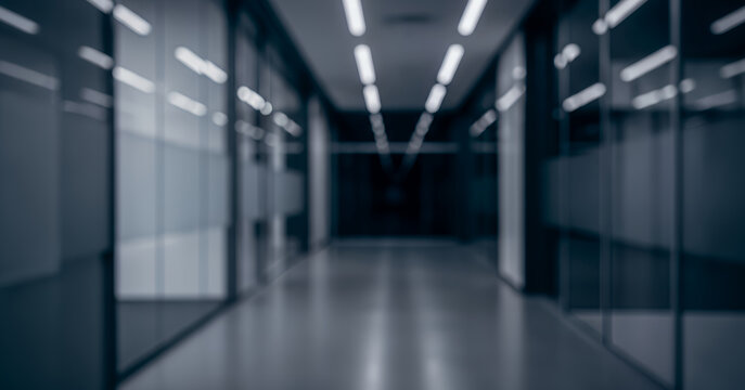 Futuristic office corridor shown in intentional blur, highlighting symmetry, glass partitions, cool tones, and modern lighting for abstract business, technology, and corporate background concepts.