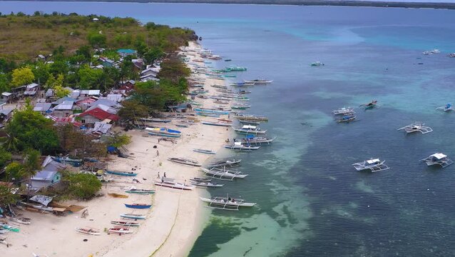 Drone shot of tropical shoreline with boats and clear shallow water