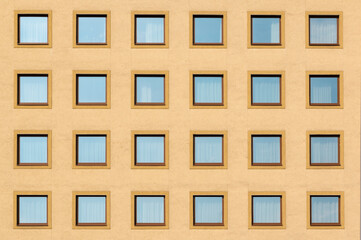 Obraz premium Multiple square windows of a residential flat apartment building from the font with yellow walls, abstract modern architecture exterior, minimal ist urban style