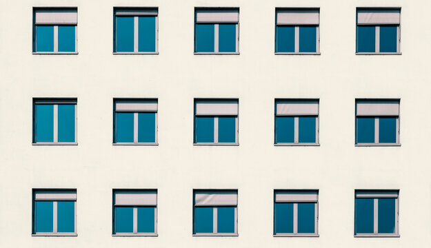 Multiple windows of a residential flat apartment building from the font with white cream walls, abstract modern architecture exterior, minimal ist urban style
