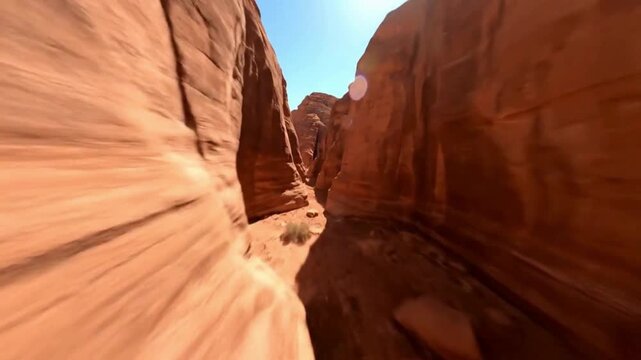 An adventurer's view through a narrow sandstone canyon carved by eons of wind and water, the towering walls create a breathtaking natural tunnel.  FPV drone perspective landscape animation