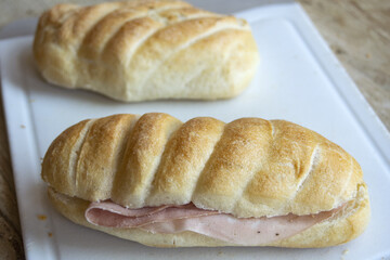 ham sandwich roll with crusty bread on white cutting board