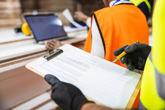 Worker checking inventory list at lumberyard