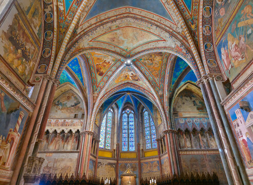 Assisi's Upper Basilica transept, featuring Cimabue's frescoes, starry Gothic vaults, and 13th-century stained glass windows. A vibrant masterpiece of medieval Italian art