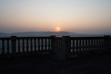 View from a terrace with column railing to the sea  at sunset