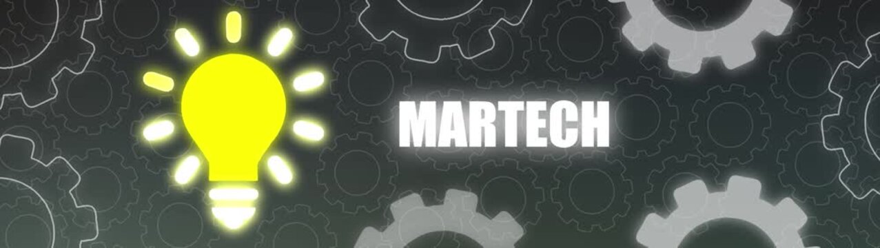 Bright Yellow Light Bulb Shines Next to the Word Martech Surrounded by Interlocking Gears on a Dark Backdrop