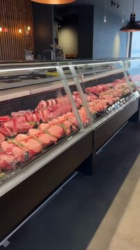 Video of a butcher shop with a low-angle view showcasing a variety of meats in a display case.