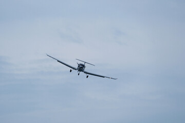 Single-engine plane approaching the airport under a cloudy sky
