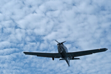 Single-engine plane approaching the airport under a cloudy sky