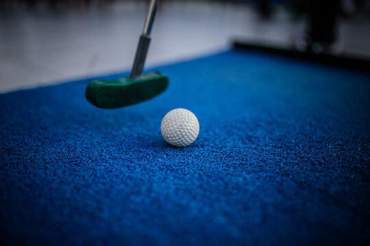 The image shows a mini golf set, a miniature version of golf focused exclusively on putting. The set includes specialized putters and lightweight golf balls designed for artificial turf or indoor play