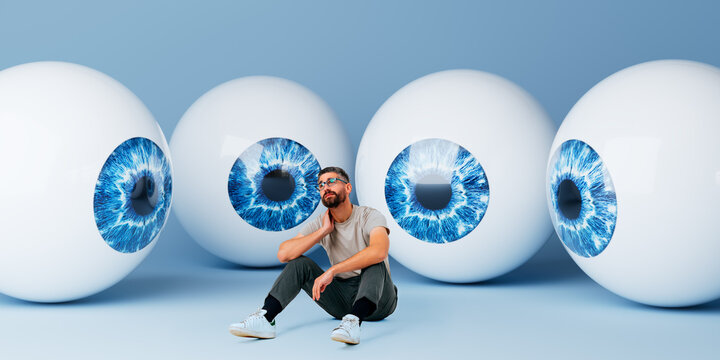 Man sitting in studio surrounded by oversized 3D eyeball spheres