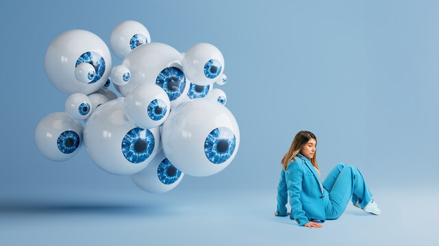 Woman sitting on studio floor beside floating cluster of oversized 3D eyeballs