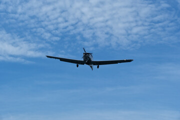 Single-engine plane approaching the airport under a cloudy sky