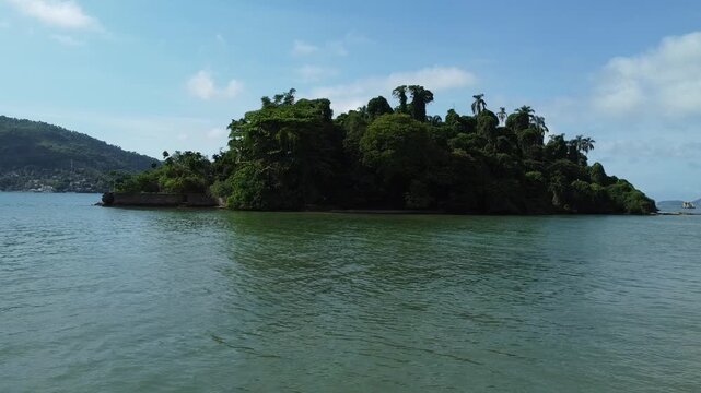 Slow drone approach towards the small tropical Island Ilha do Coqueiro in the Bay of Angra dos Reis, covered in dense Atlantic rainforest