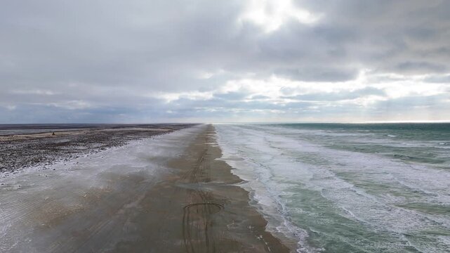Caspian Sea coastline near Aktau, Mangystau region, Kazakhstan, captured in a top-down aerial drone shot featuring powerful green-blue sea waves rolling onto an empty yellow-brown sandy shore. Winter 