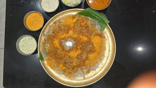 Delicious and soft Benne Open podi Dosa in dvg restaurant served in brass plate with different chutneys and sambhar. White butter on benne dosa