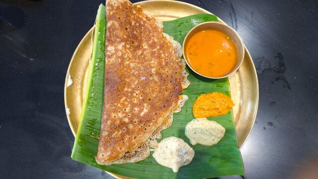 Tasty Benne pudi dosa served with three chutneys and sambar at dvg benne dosa restaurant on banana leaf and brass plate. white butter soft podi dosa