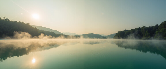 Magic mist rising over emerald lake at dawn with mountains in background  
