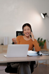 Asian woman manages freelance tasks from home with laptop