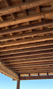 shot rustic wooden ceiling features rows exposed beamed rafters deliberate gaps allowing filtered sunlight