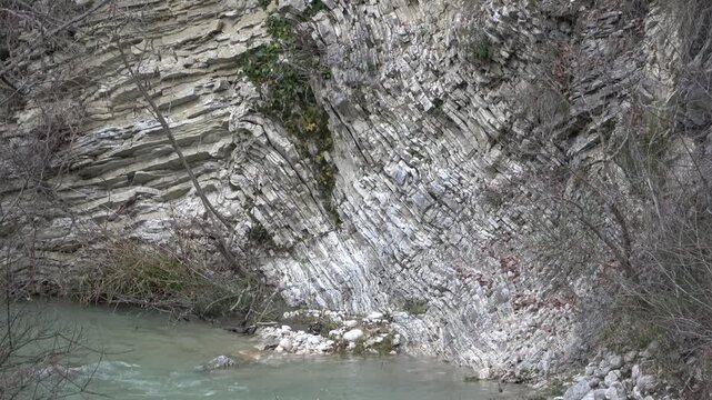 Geological formation of stratified rocks along the course of a mountain stream.