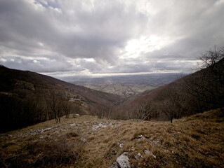 Paesaggio montano, campi coltivati e fiume nella valle illuminata dal sole