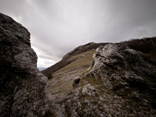 Formazione rocciosa naturale su pendio montano con masso scolpito dal tempo