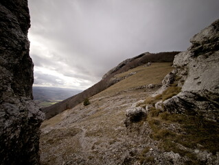 Formazione rocciosa naturale su pendio montano con masso scolpito dal tempo