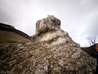 Formazione rocciosa naturale su pendio montano con masso scolpito dal tempo